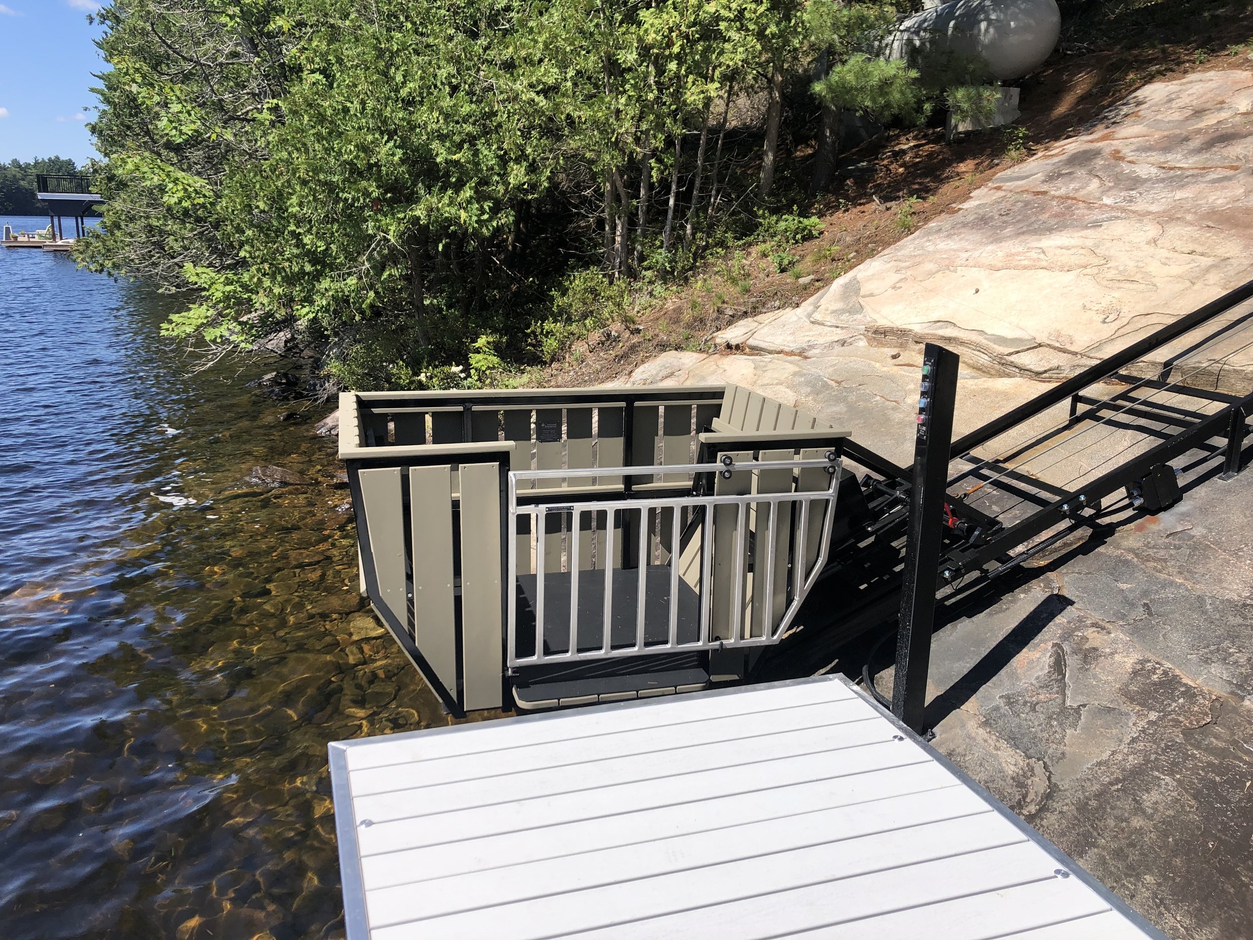 The removable dock section connecting the boathouse to the lift fits perfectly. People and supplies travel from the dock all the way to the kitchen without climbing any stairs, and the car is big enough that a dolly or wagon can roll things straight to the cottage. The lower button box is attached directly to the rock, so it can stay put through the winter.