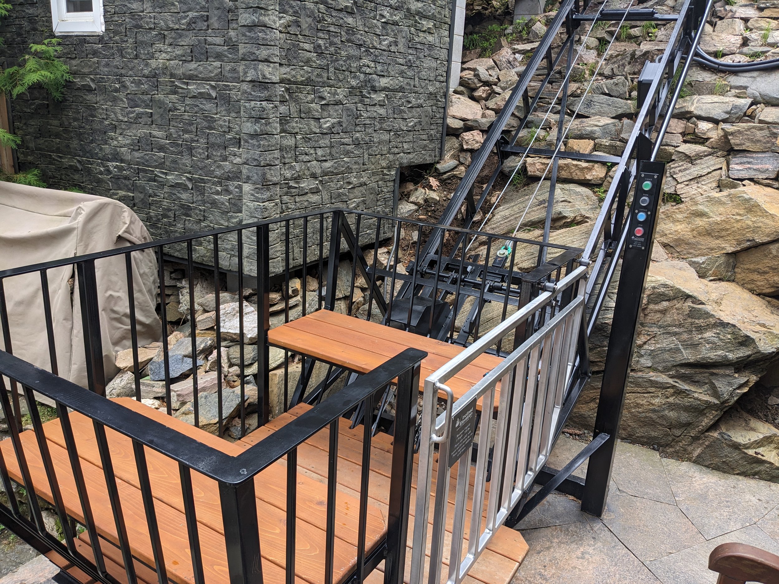 This photo highlights the minimal clearances at the bottom station. The lift's PARK button moves the car up the track when it is not in use, keeping the walkway clear. Perfectly designed for a small space.