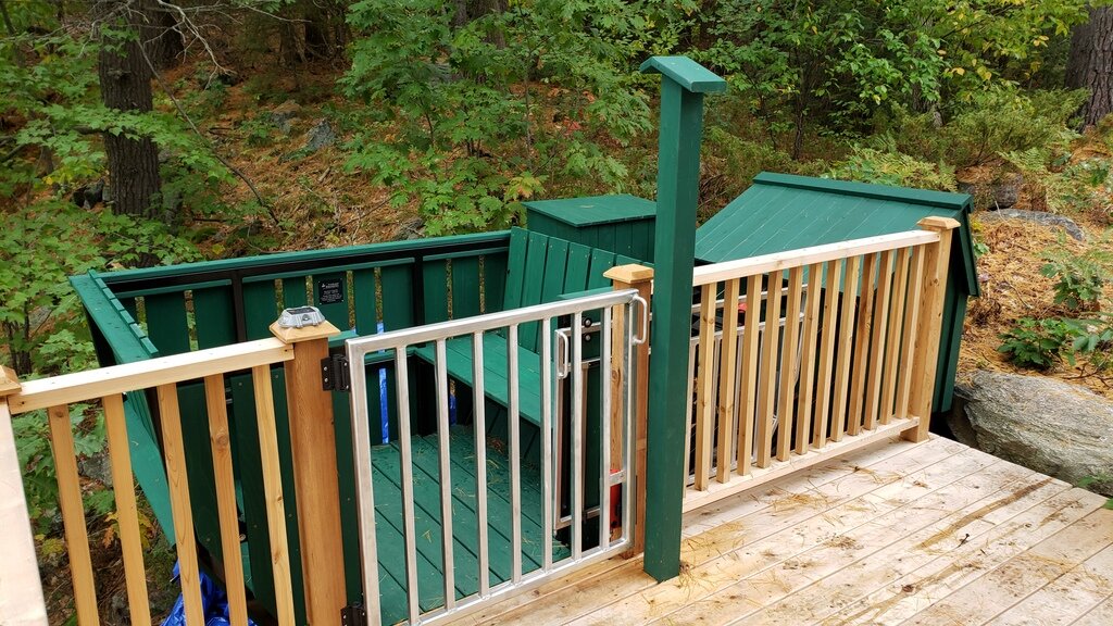 The upper station has a small access platform and an interlocked gate. The gate only opens when the car is stationary in the station, and the car only leaves when the gate is closed and latched. An override allows the car to be brought to the bottom and ridden back to the top if the gate did not close properly. Another view of the access platform—the cottage sits behind the camera, connected by a short boardwalk.