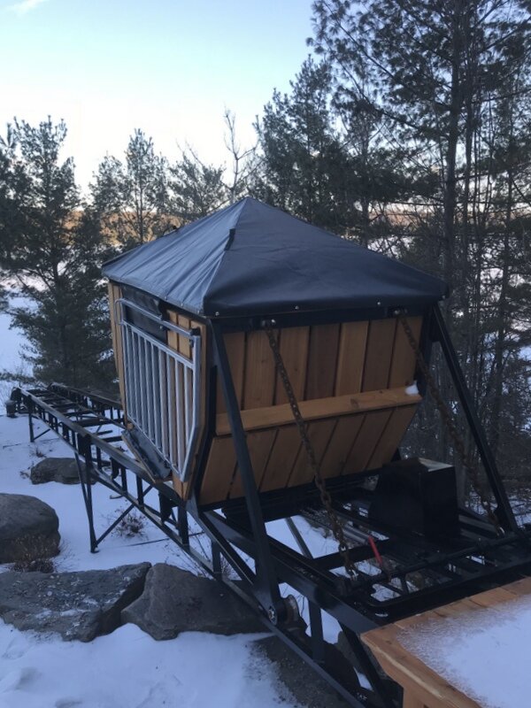 A wintry photo of the car under its winter cover. The cover has an aluminum frame and a durable skin, held down by a single fastener.