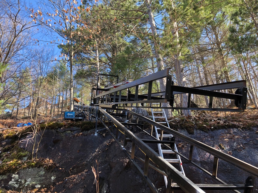 Another view of the installation hoist carrying a 20-foot section of track to the third pitch. Above the hoist are the 220 feet of track leading to the cottage, just visible in the background.